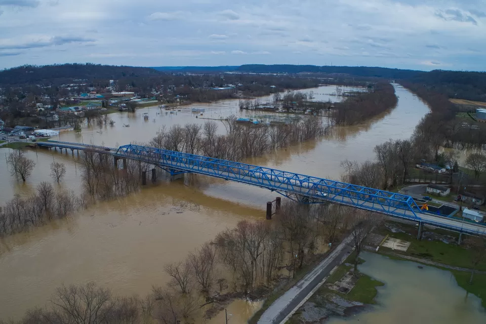 Aerial view of a blue bridge over a wide, flooded river in Kentucky.